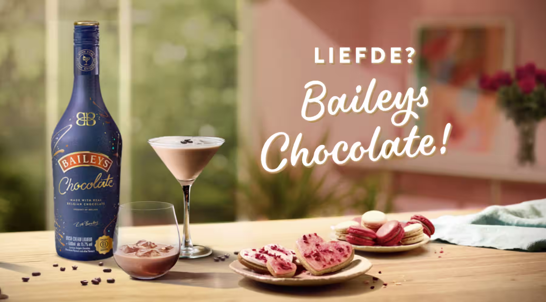 Twee flessen Baileys Original Irish Cream met chocoladecocktails, koekjes en bloemen op een romantische achtergrond met Valentijnsdag als thema.